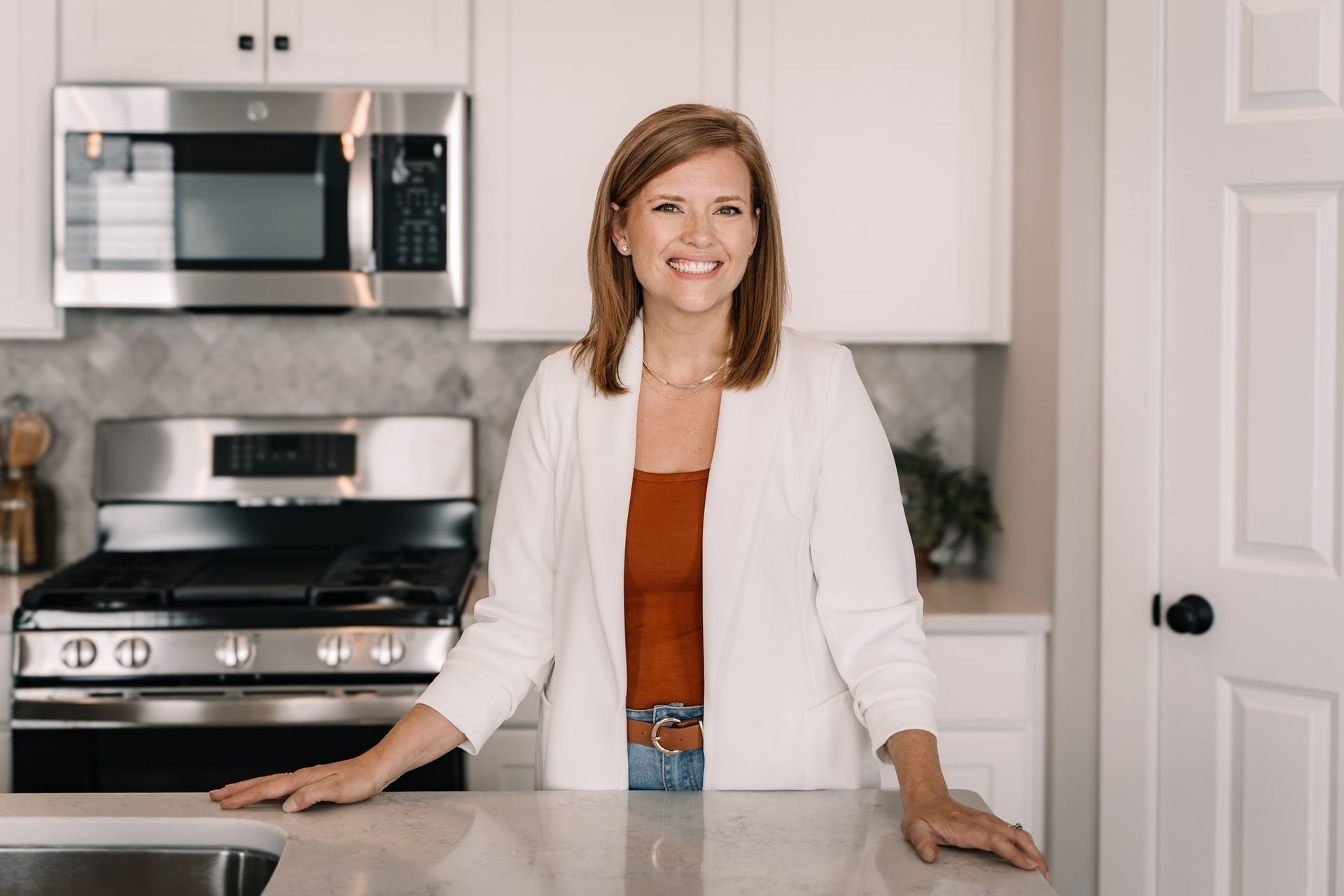A woman is standing in a kitchen next to a stove.