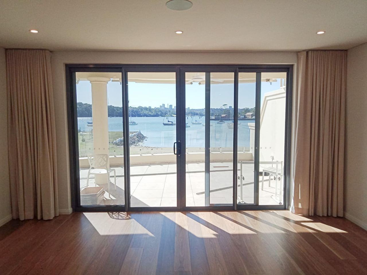 An Empty Room With Sliding Glass Doors Leading — Ron Ayton Curtains, Blinds & Shutters In Gwandalan, NSW