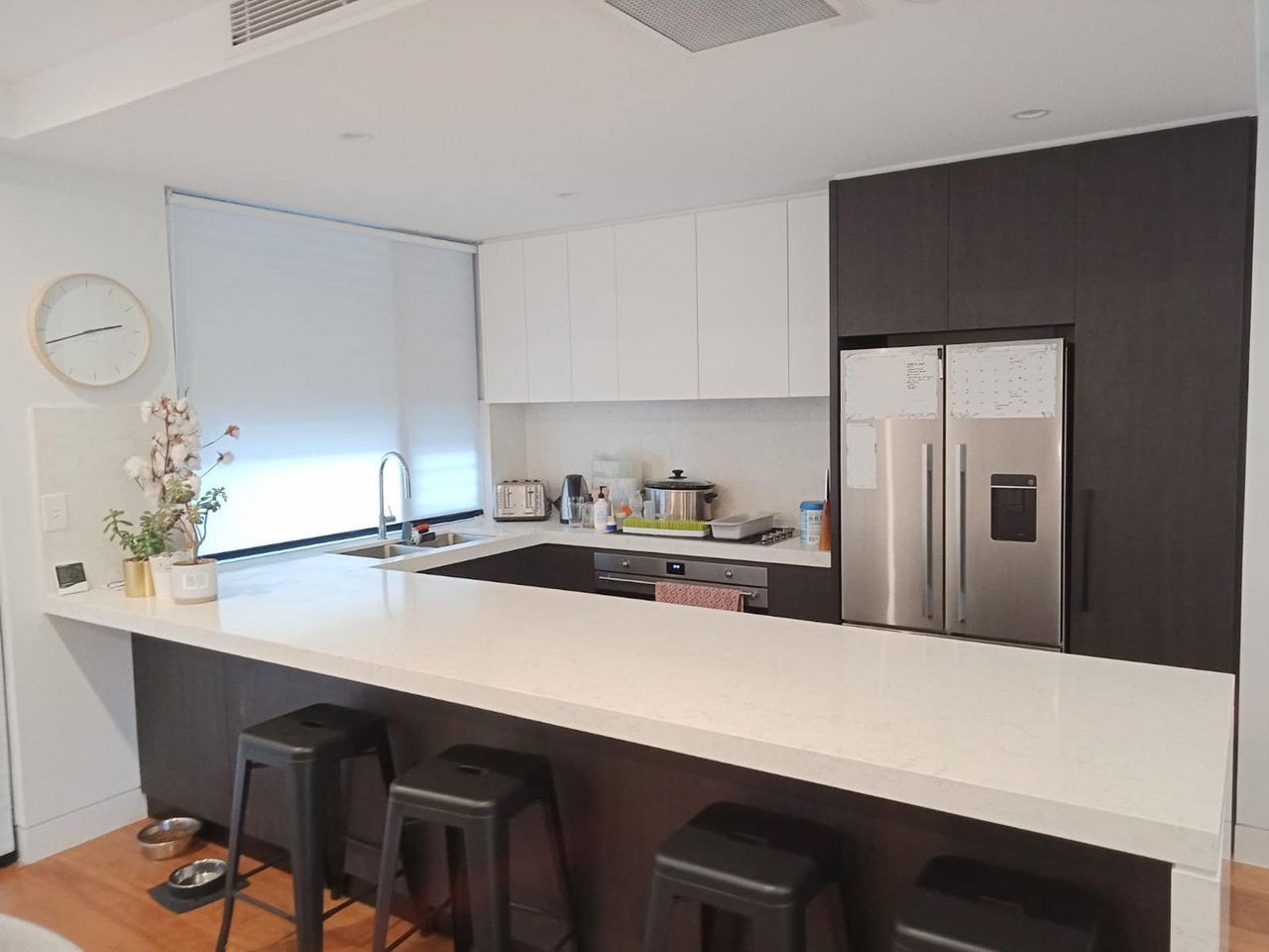 A Kitchen With Stools And A Clock On The Wall — Ron Ayton Curtains, Blinds & Shutters In Avoca, NSW
