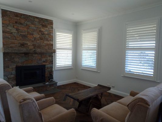 A Living Room With A Fireplace And Two Chairs — Ron Ayton Curtains, Blinds & Shutters In Shelly Beach, NSW