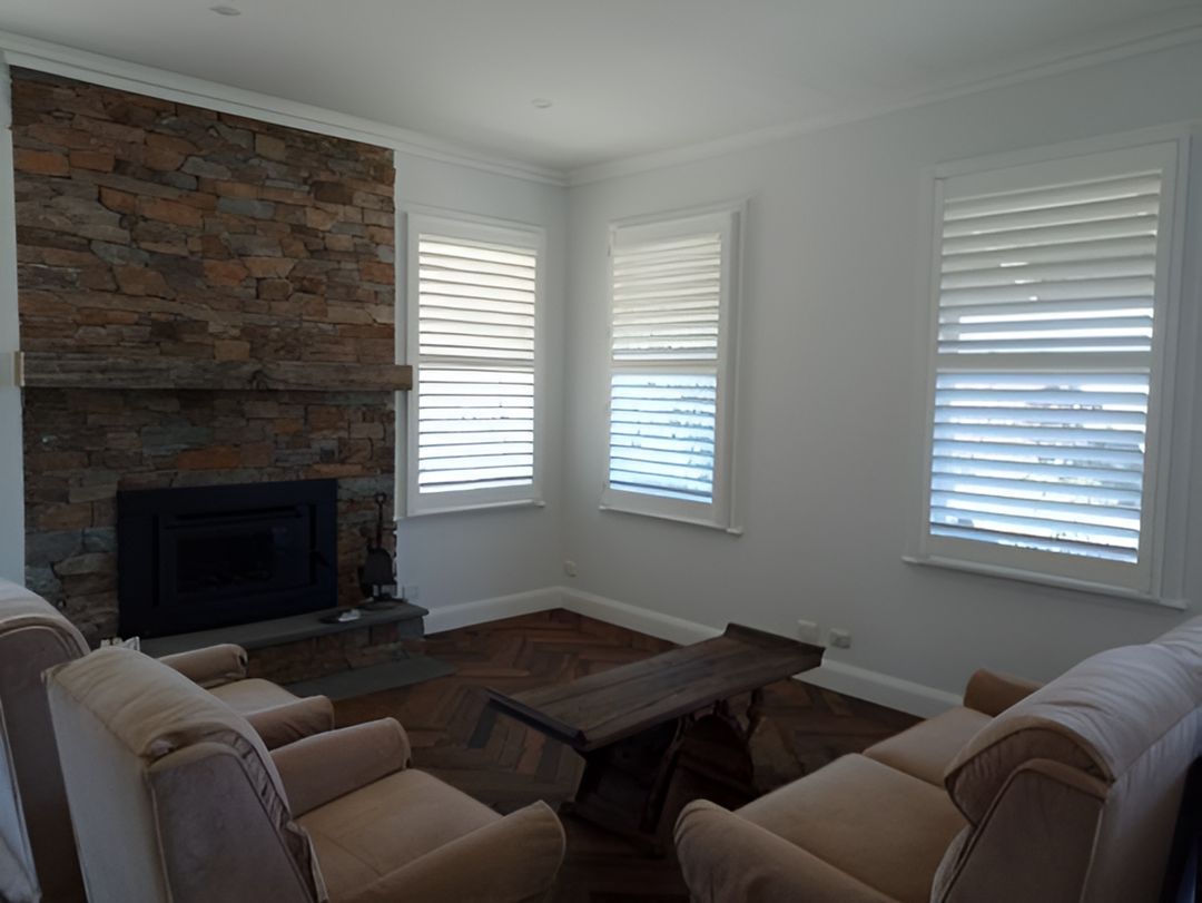 A Living Room With A Fireplace, Chairs, And A Table — Ron Ayton Curtains, Blinds & Shutters In Wyee, NSW