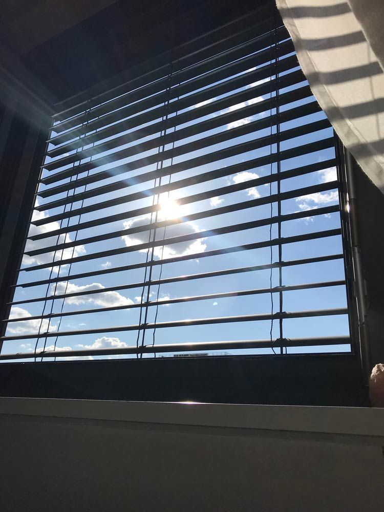 The Sun Is Shining Through The Blinds Of A Window — Ron Ayton Curtains, Blinds & Shutters In Shelly Beach, NSW