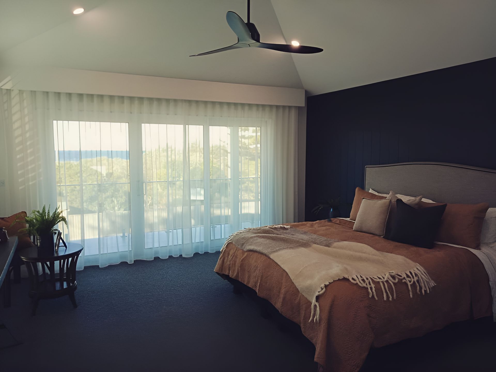 A Bedroom With A Large Bed And A Ceiling Fan — Ron Ayton Curtains, Blinds & Shutters In Shelly Beach, NSW
