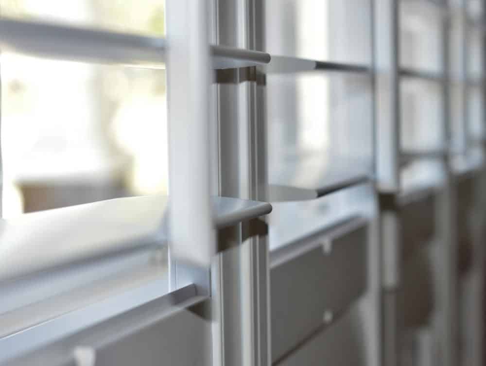 A Close Up Of A Metal Railing Between Two Windows — Ron Ayton Curtains, Blinds & Shutters In Shelly Beach, NSW