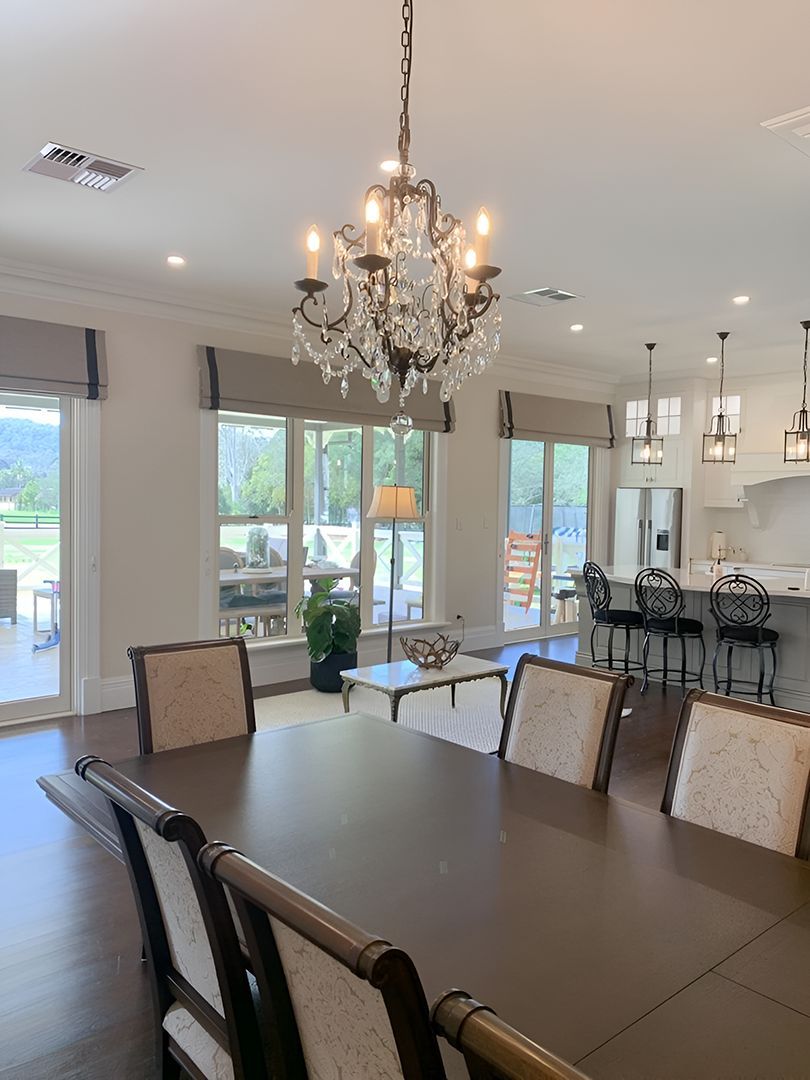 A Dining Room With A Chandelier Hanging From The Ceiling — Ron Ayton Curtains, Blinds & Shutters In Shelly Beach, NSW