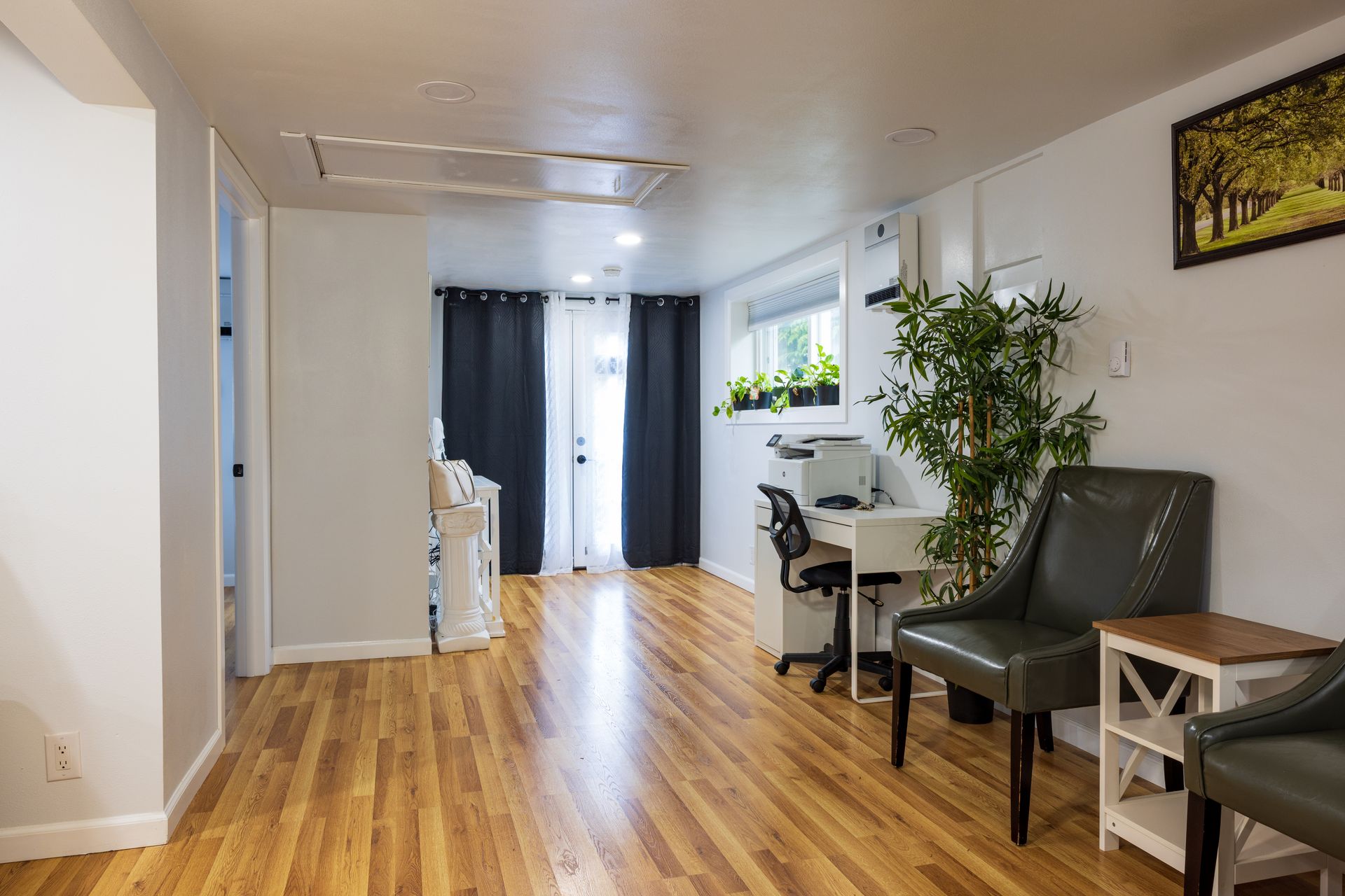 Long, wood-floored room with desk, chairs, and a door to the outside.