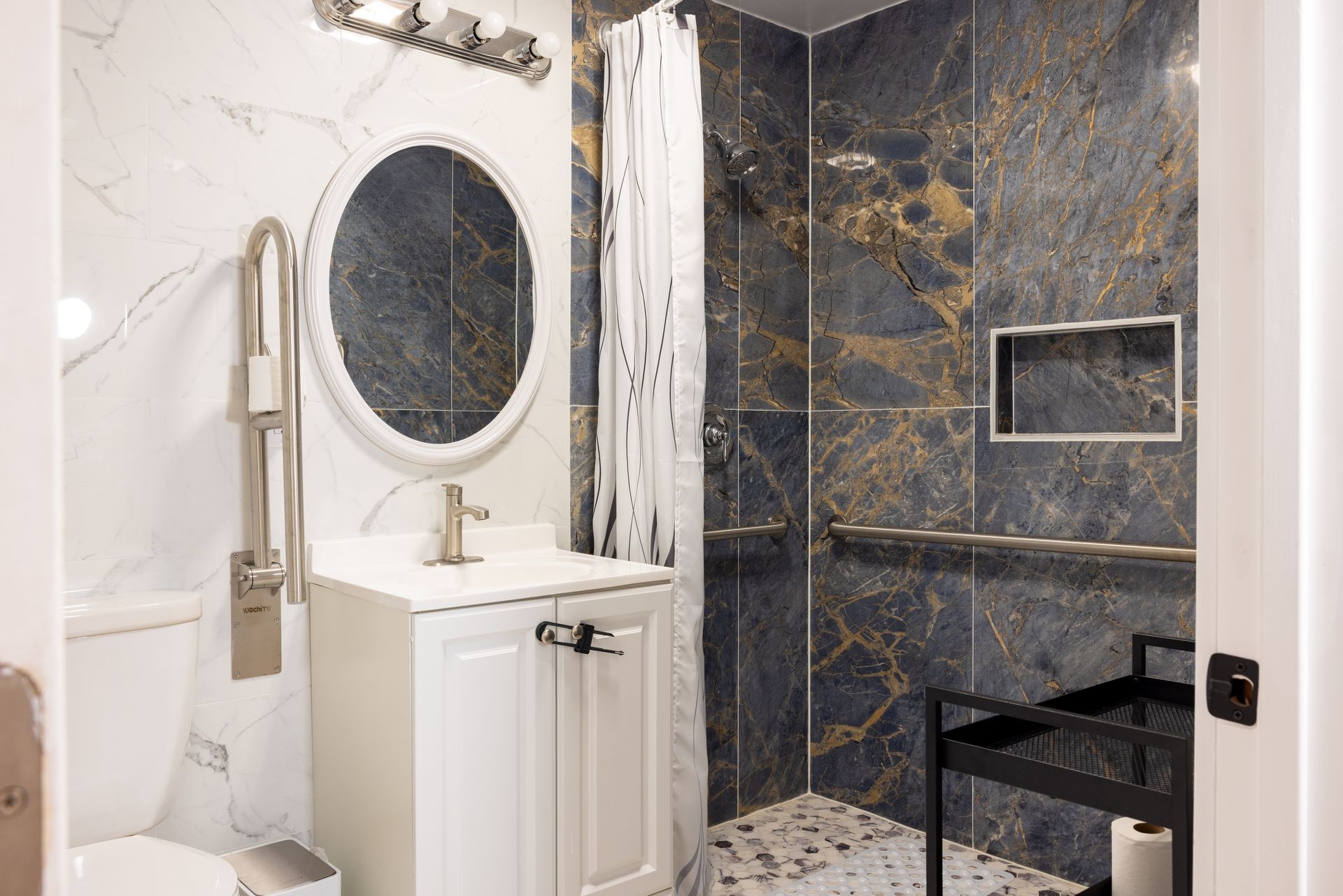 Accessible bathroom with a walk-in shower, grab bars, marble tiles, and a vanity.