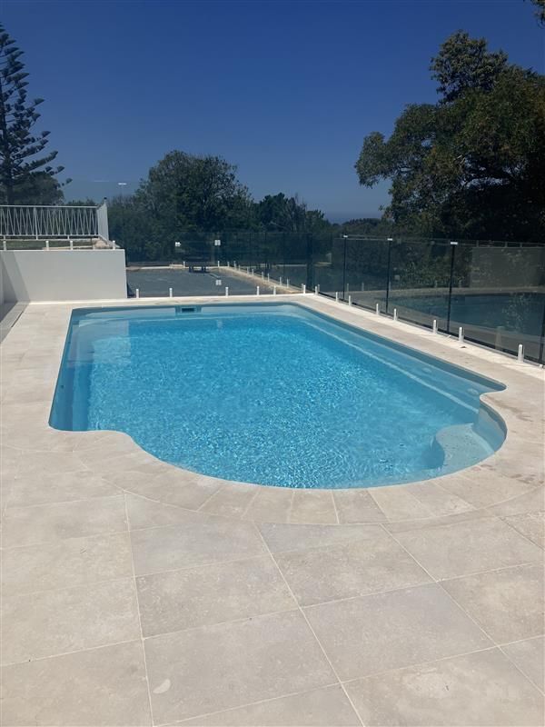 A large swimming pool with a glass fence around it — Steve Merrick Family Swimming Pools in Diamond Beach, NSW
