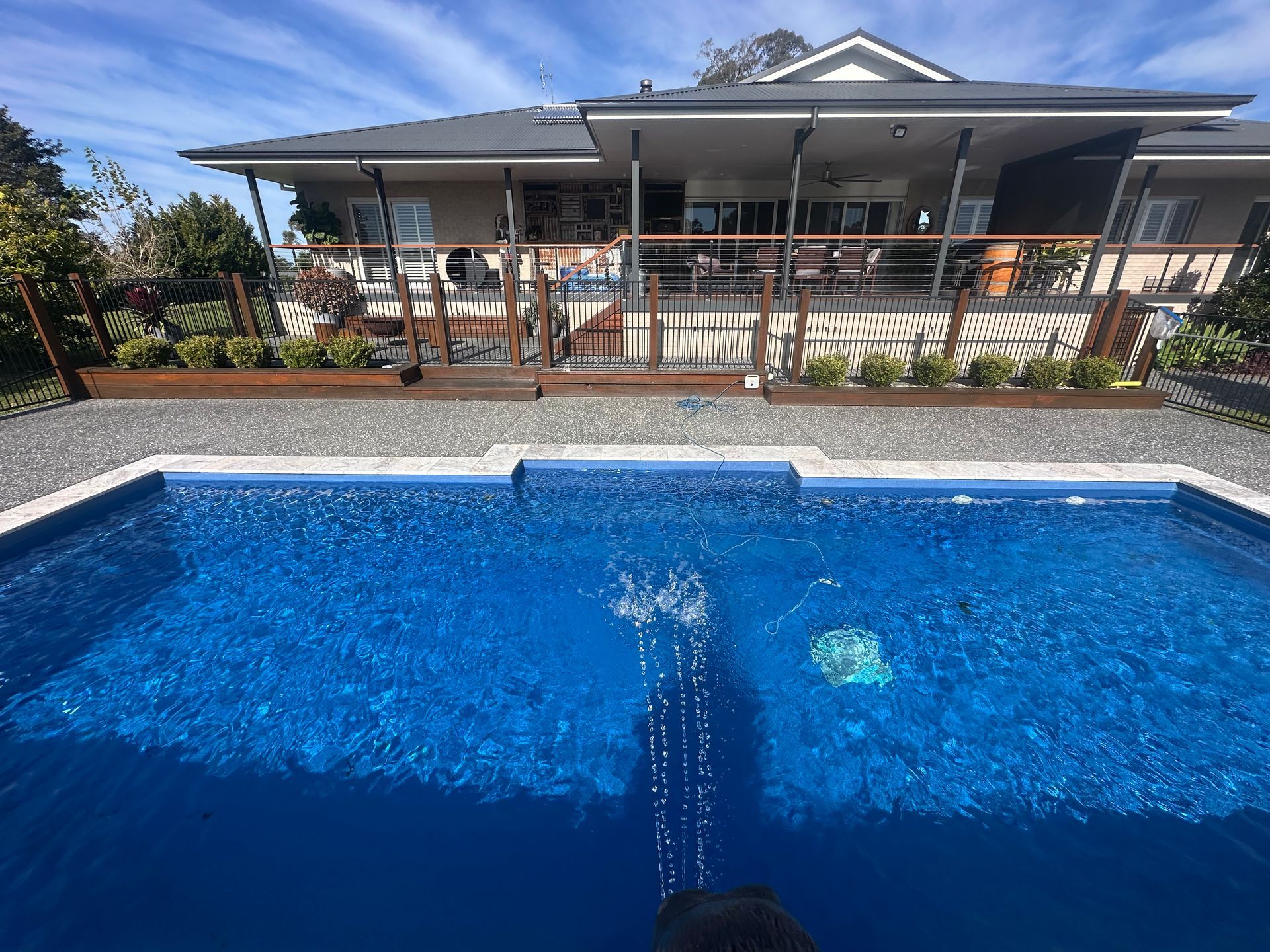 A Swimming Pool is Surrounded by a Fence and a Pergola — Steve Merrick Family Swimming Pools in Diamond Beach, NSW