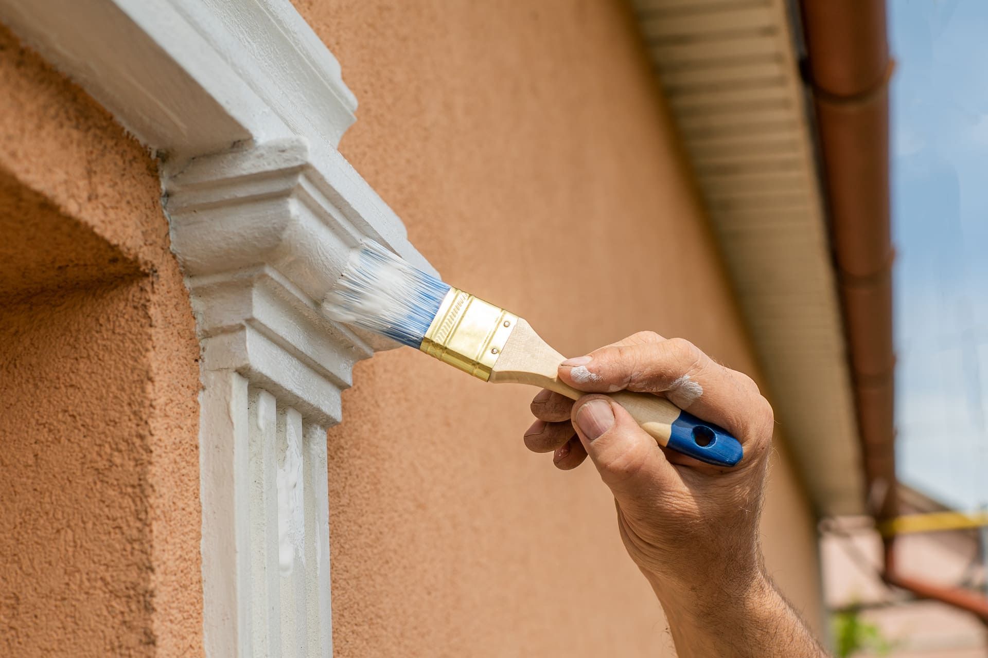 house care The master uses white paint with a brush to paint the windows. close-up house repair