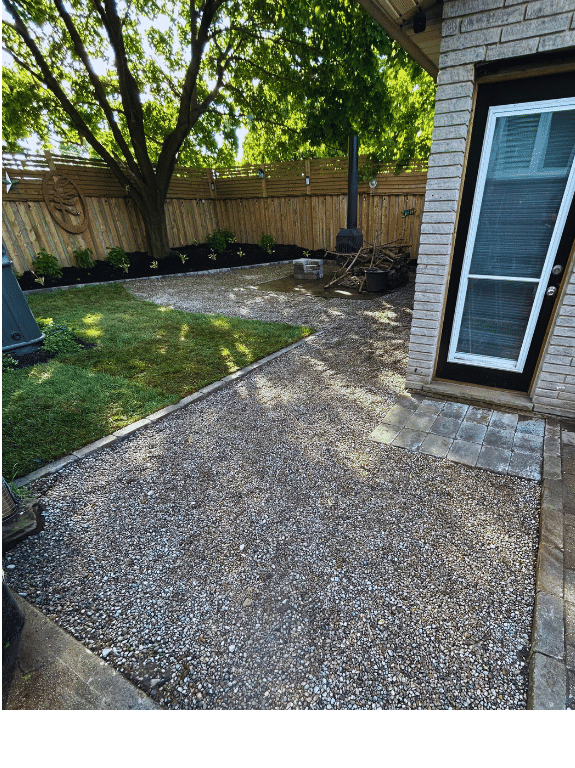 A backyard with a gravel walkway leading to a brick house.
