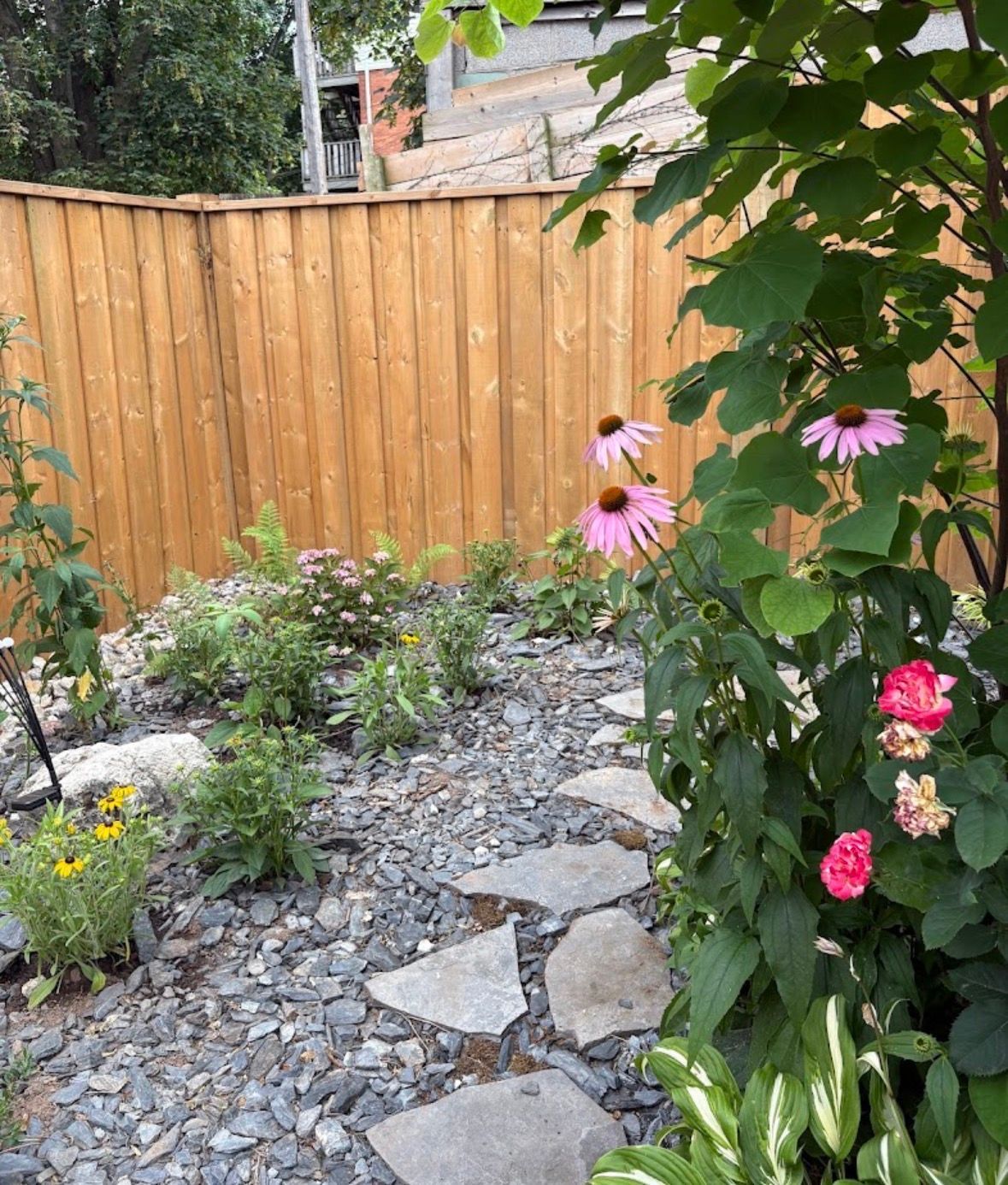 A garden filled with lots of pink and purple flowers and stairs.