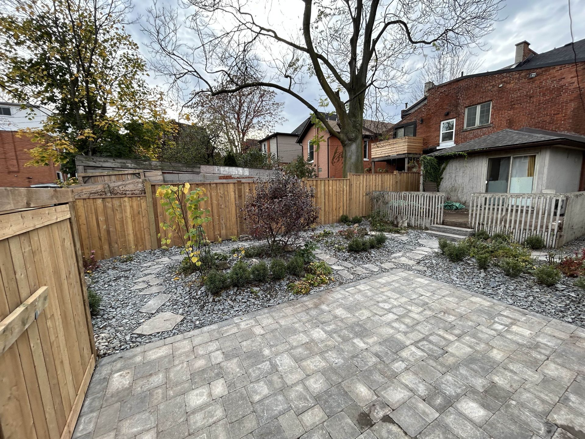 A backyard with a brick patio and a wooden fence.