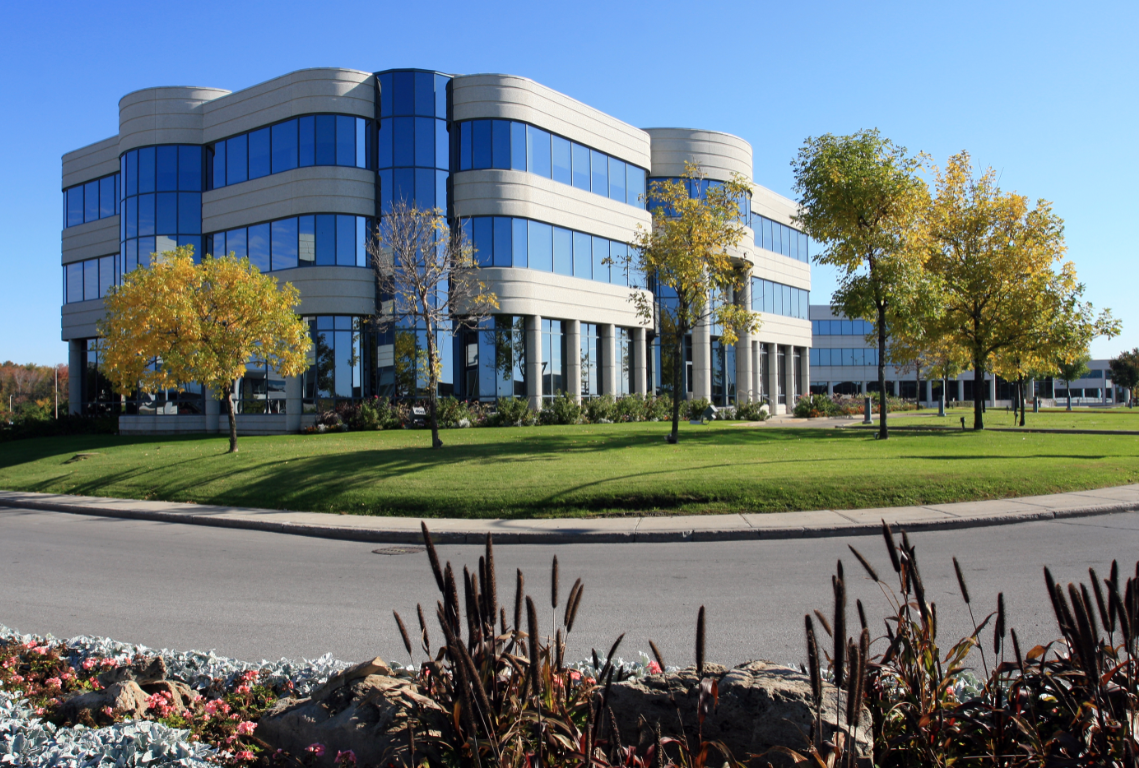 A large building with a lot of windows is surrounded by trees and grass.