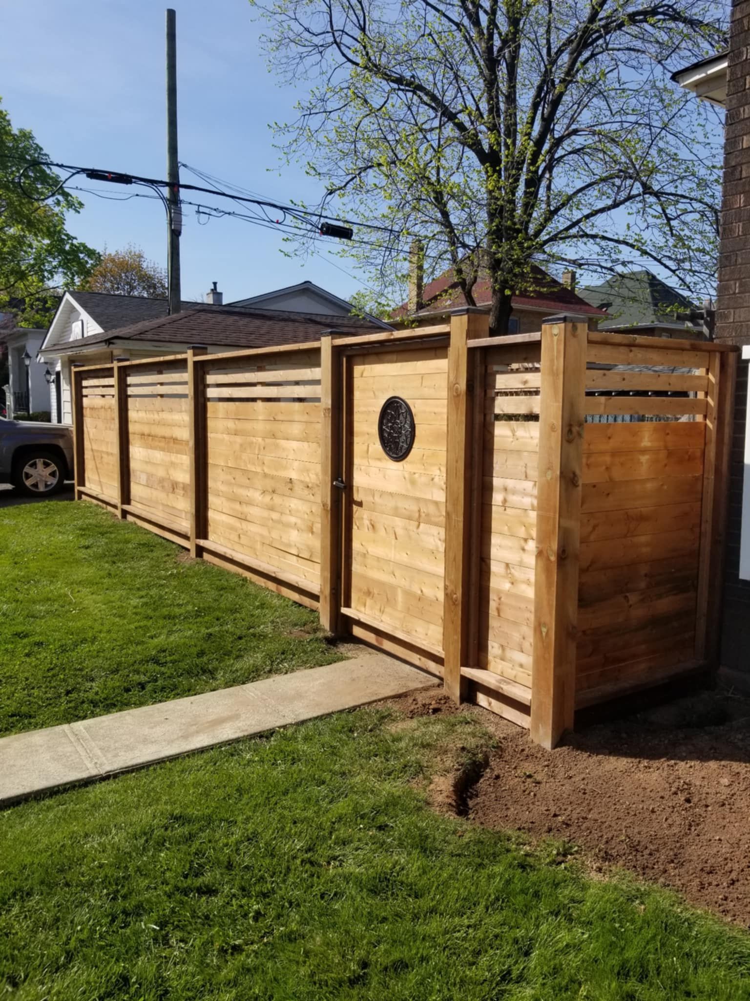 Wooden fence with gate in a yard; sunny day.