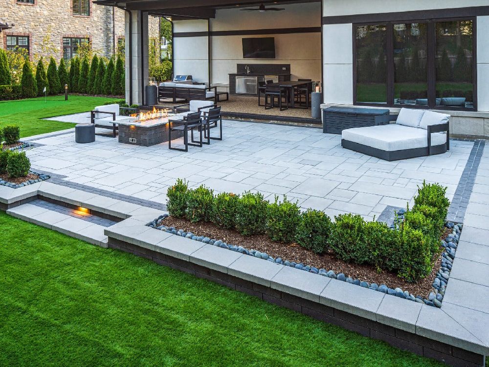 A large patio with a fire pit , couch , chairs and a television.