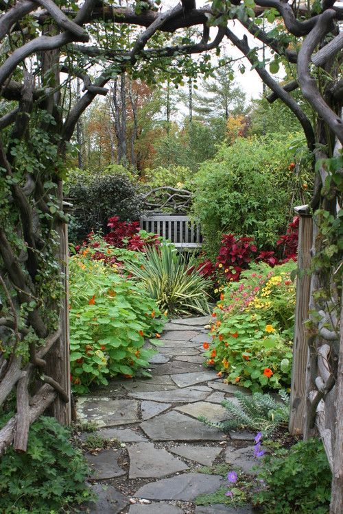 A stone path leading to a bench in a garden.