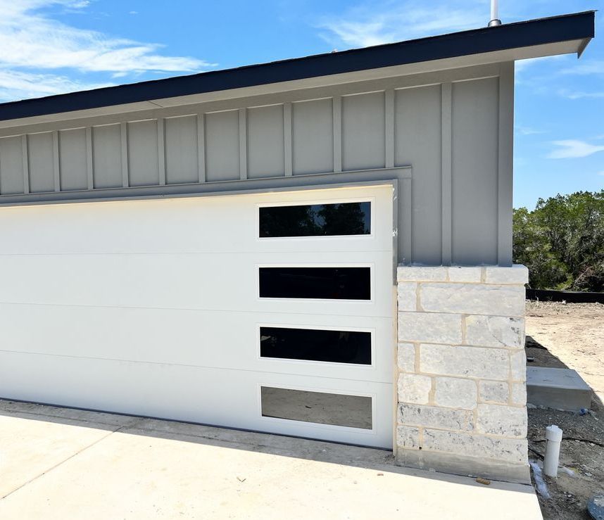 A white garage door with black stripes on it is on the side of a house.