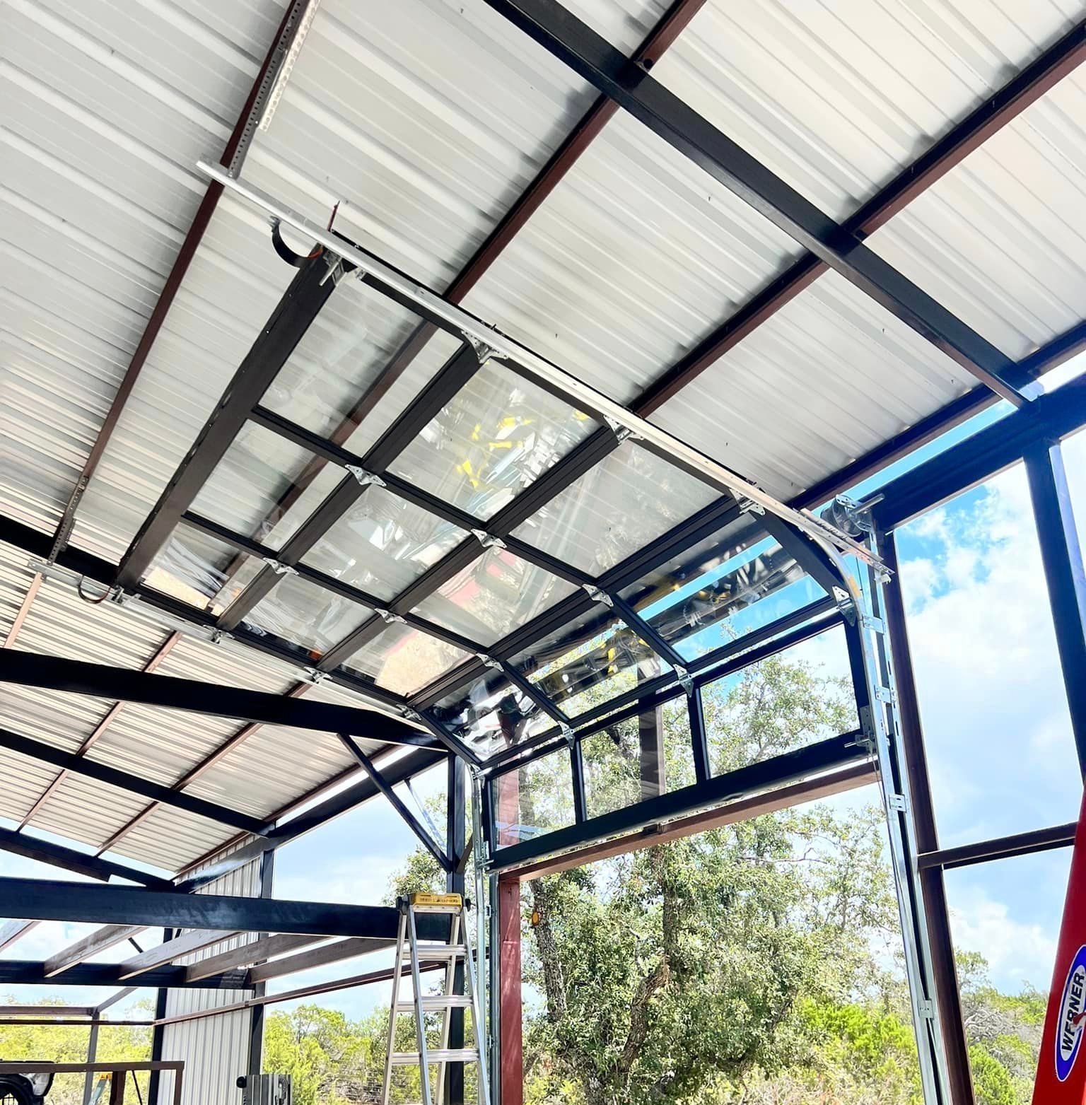 A garage door is open and a ladder is hanging from the ceiling.