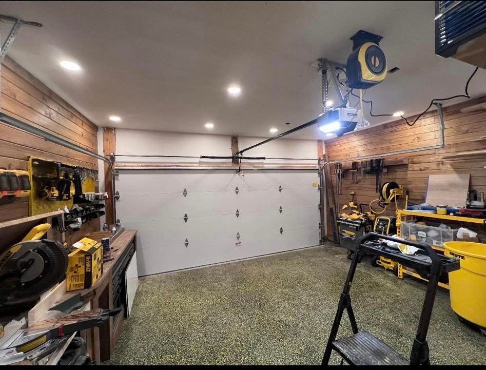 A garage with a garage door open and a ladder.