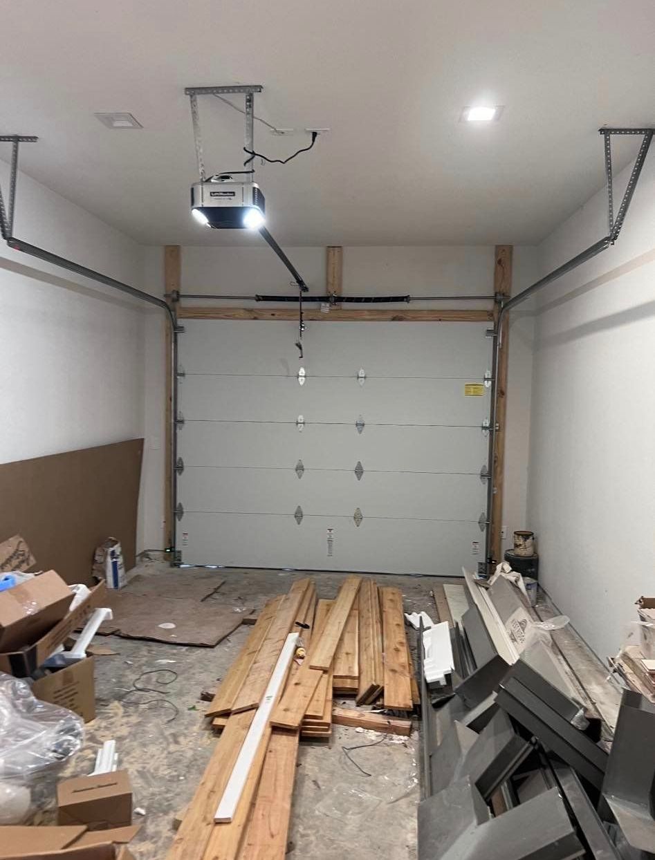 A garage with a garage door open and a lot of wood in it
