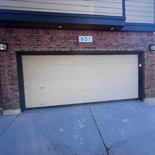 A white garage door is sitting in front of a brick building.
