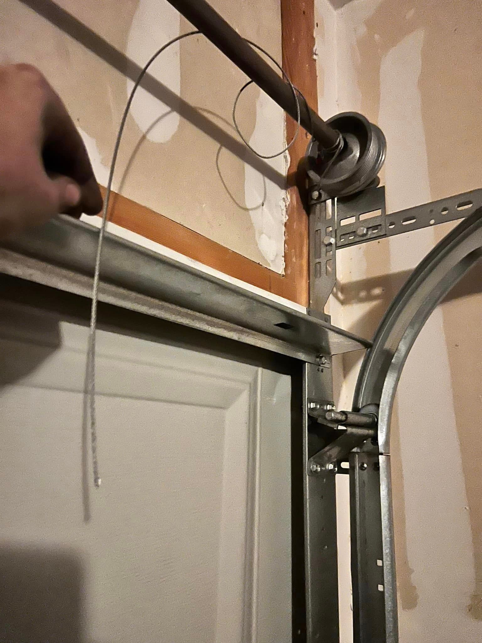 A person is fixing a garage door with a screwdriver.