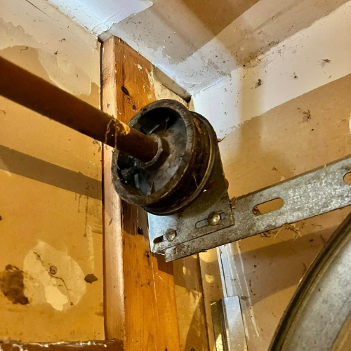 A close up of a garage door roller on a wooden wall.