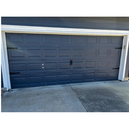 A black garage door is sitting on the side of a house.