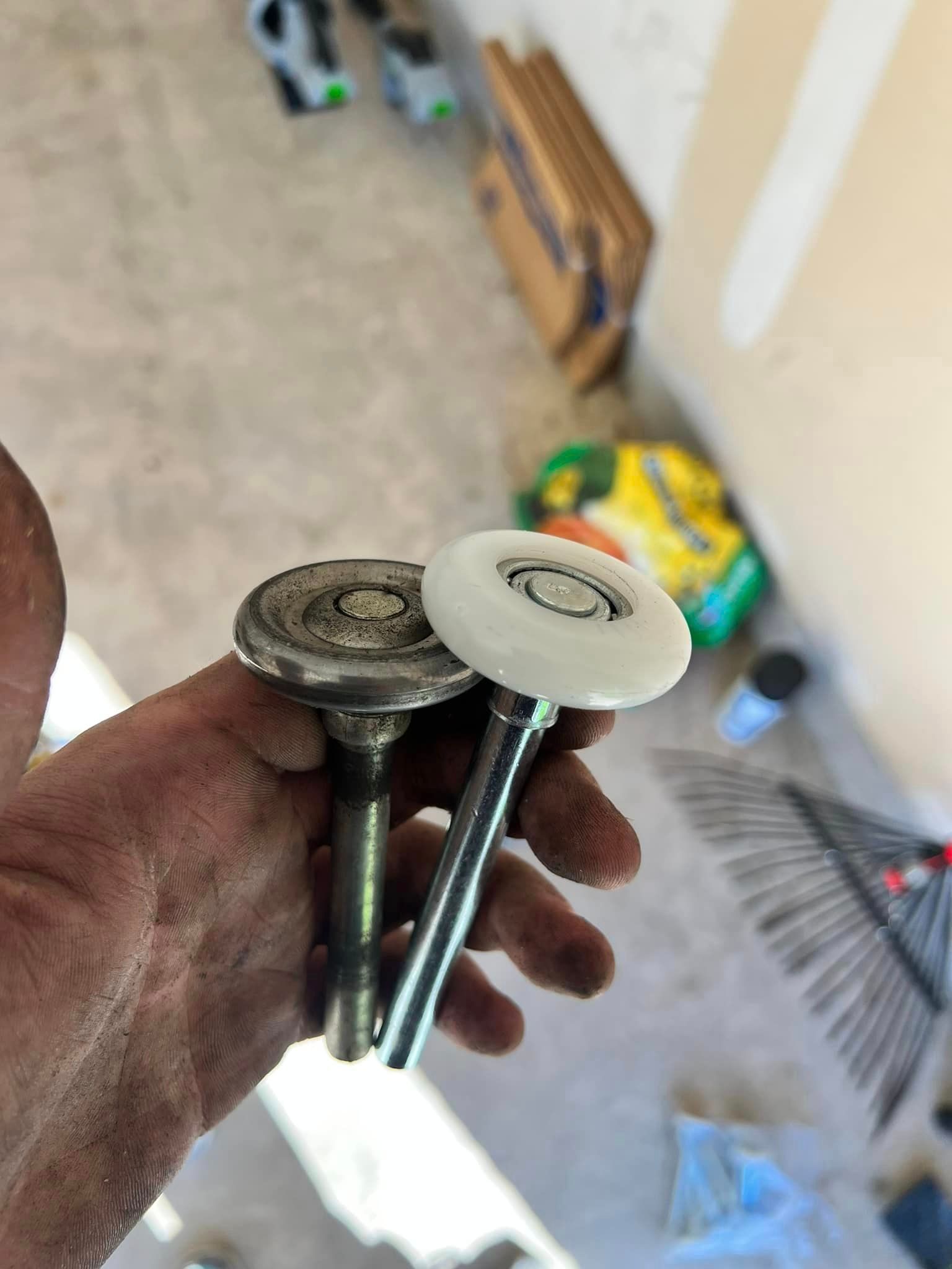 A person is holding a pair of garage door rollers in their hand.
