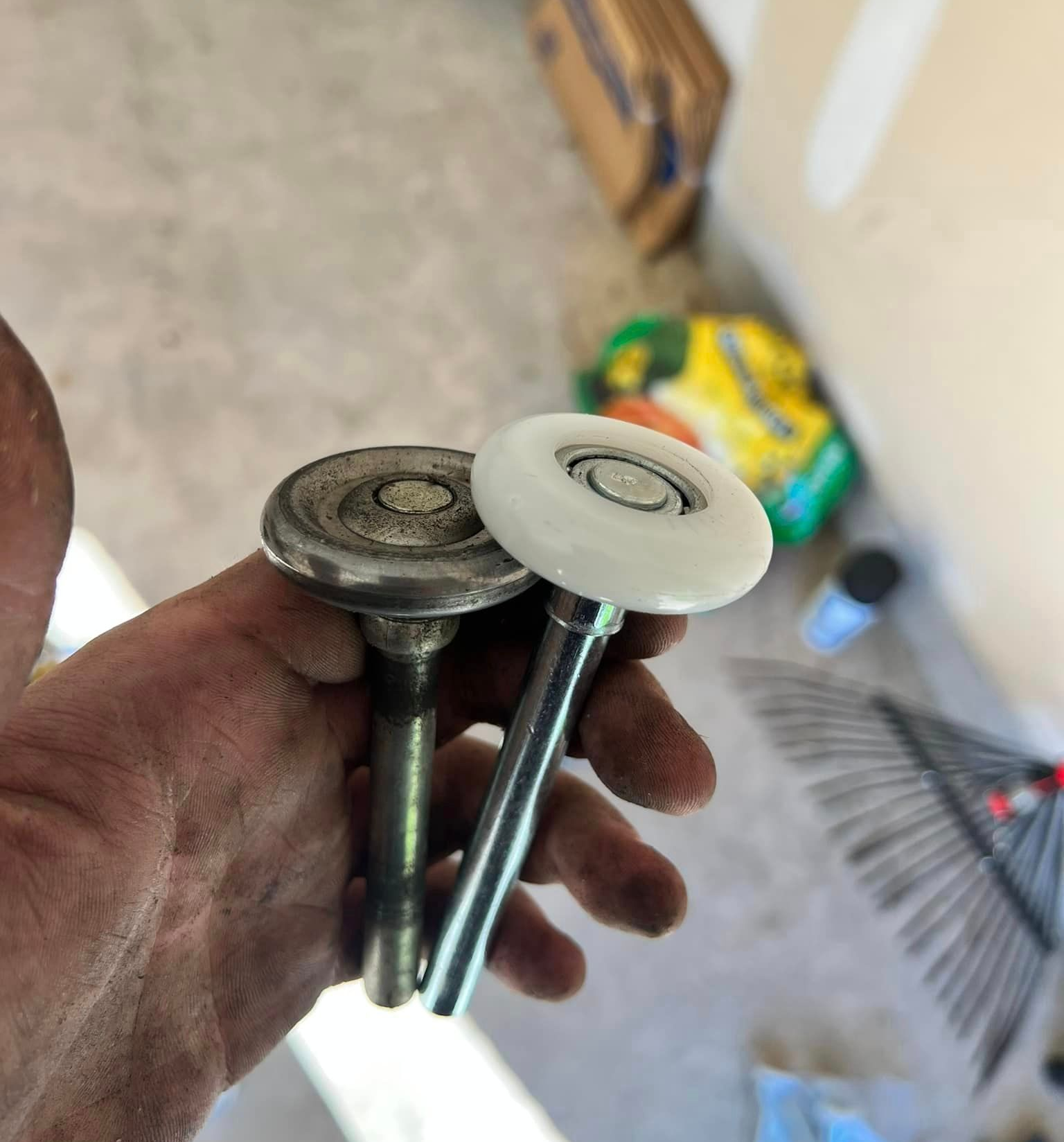 A person is holding a pair of garage door rollers in their hand.
