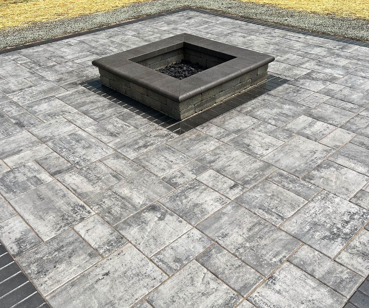Square outdoor gas fire pit on Unilock paver block patio in Northeast Ohio by Chidsey Landscape & Design.