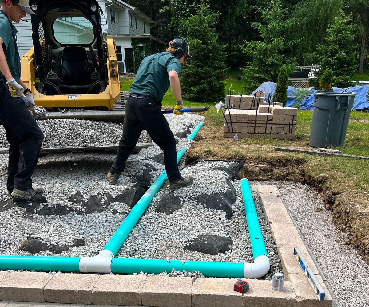 Chidsey Landscaping landscape installation crew installing drainage pipes in a Medina County backyard so that new paver patio is properly draining.