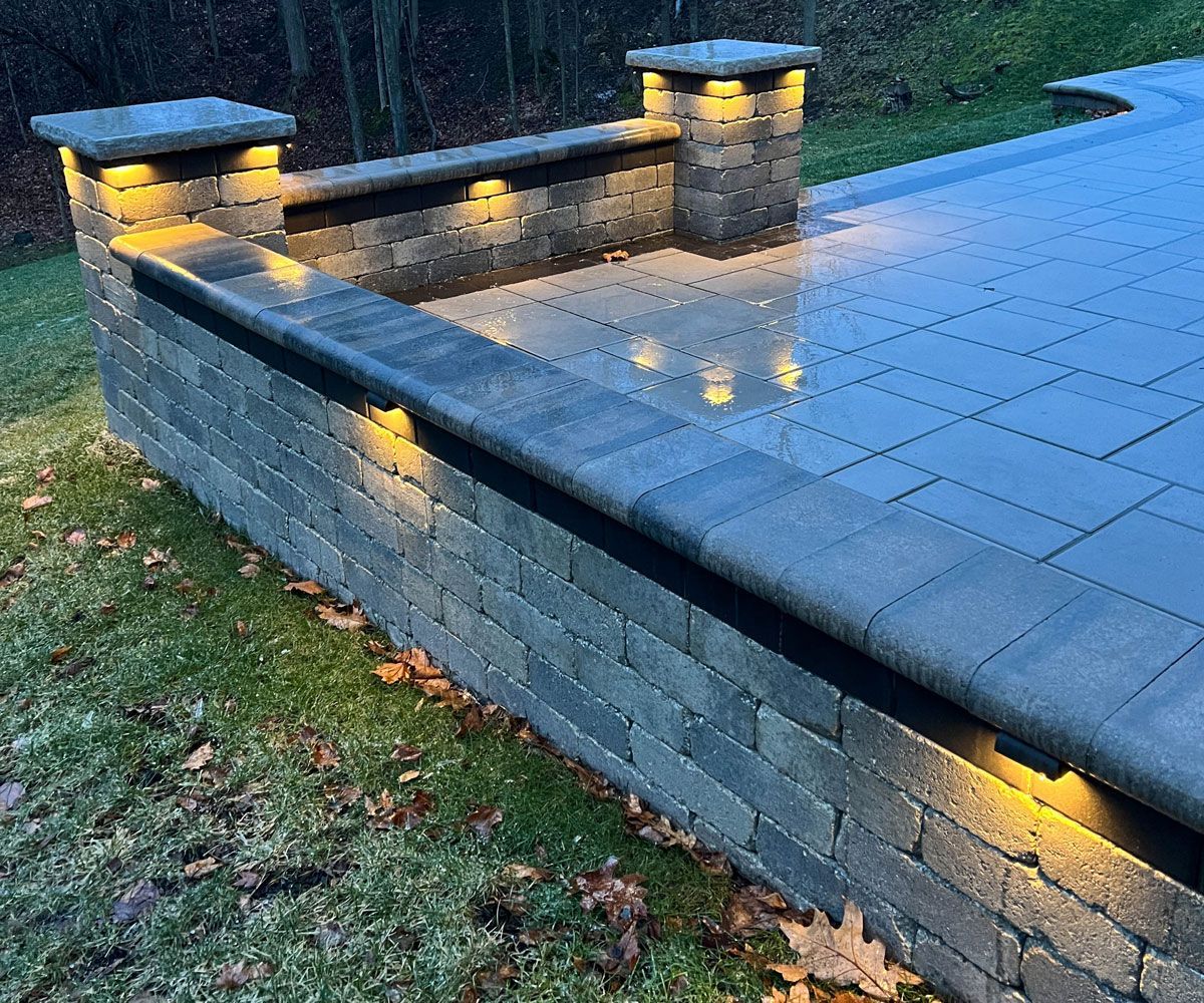 Undercap hardscape retaining wall outdoor landscape lighting in Northeast Ohio backyard Unilock paver patio by Chidsey Landscape & Design
