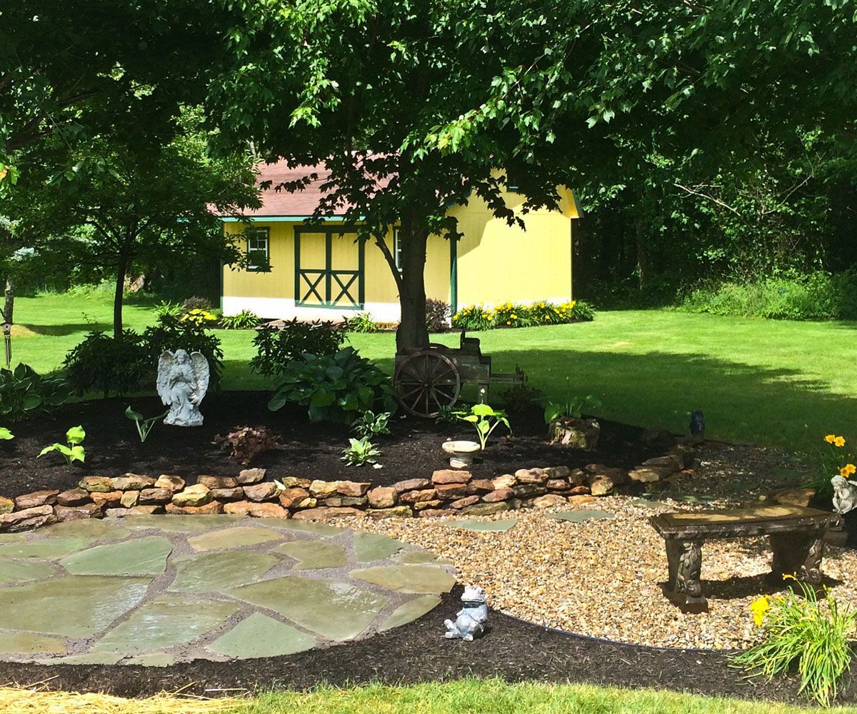 Natural flagstone patio with decorative gravel path near Medina County backyard garden bed