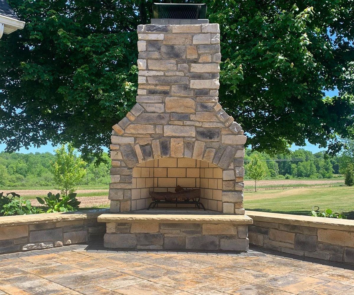 Custom stone outdoor fireplace on Fairlawn, Ohio backyard paver patio.