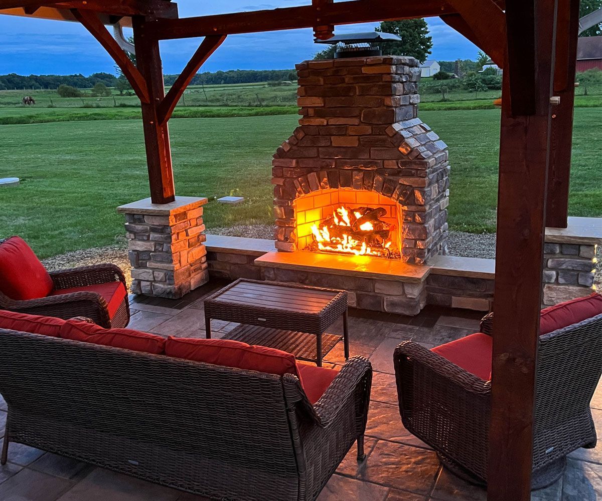 Outdoor fireplace with gas logs underneath pavilion in Medina, Ohio backyard.