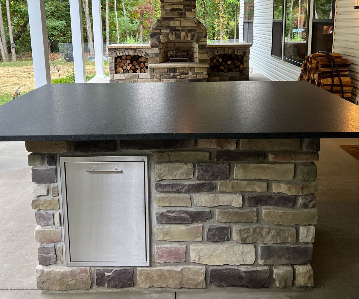 Northeast Ohio outdoor kitchen installation with bar seating and outdoor fireplace