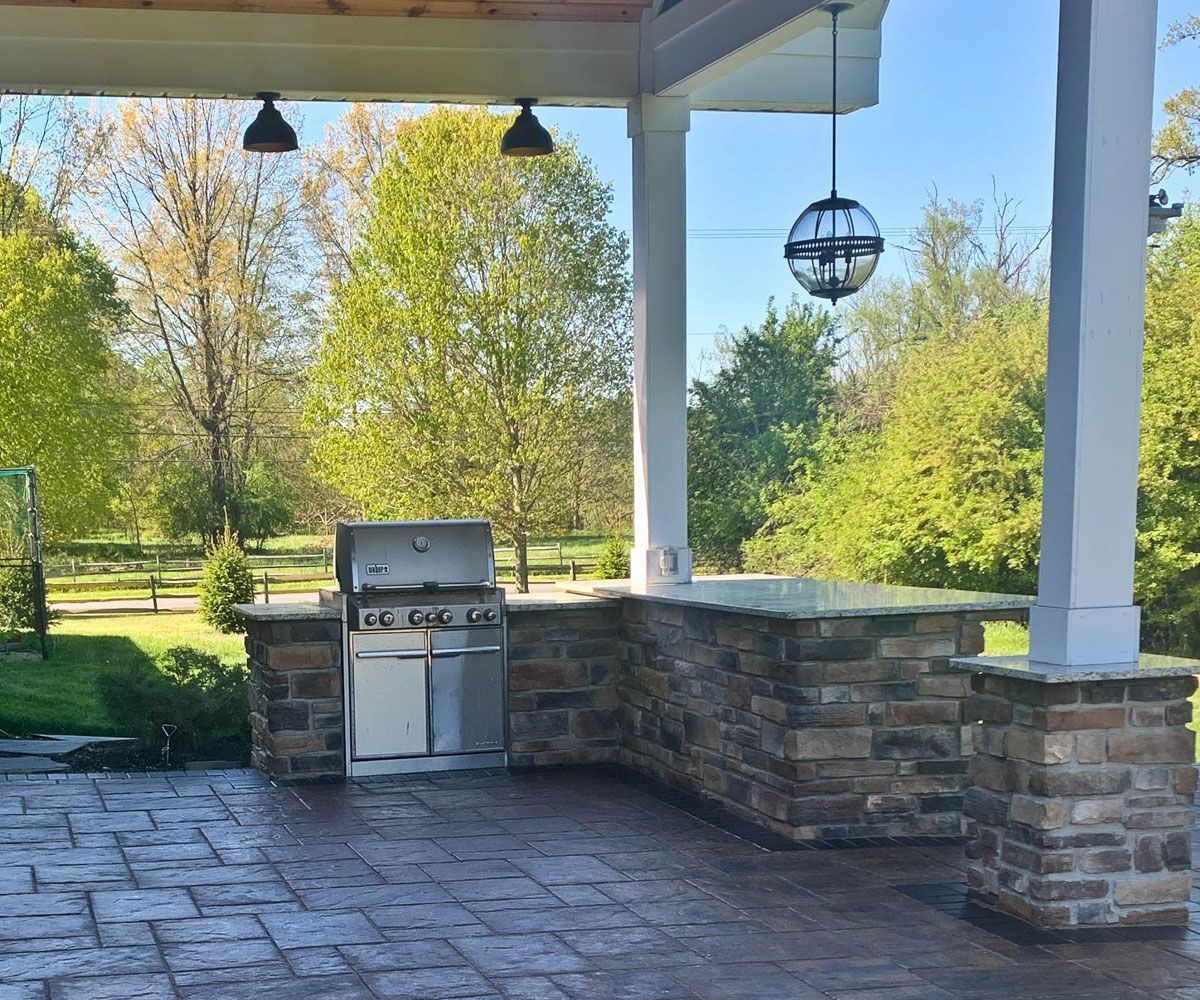 Custom outdoor kitchen covered by pavilion on Fairlawn, Ohio paver block patio by Chidsey Landscape & Design.
