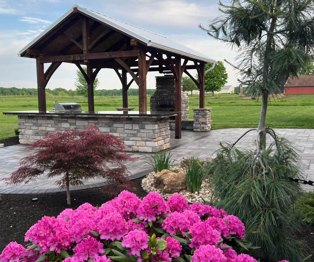 Medina County, OH outdoor living landscape design with all weather pavilion, paving stone patio, and garden beds with plantings.