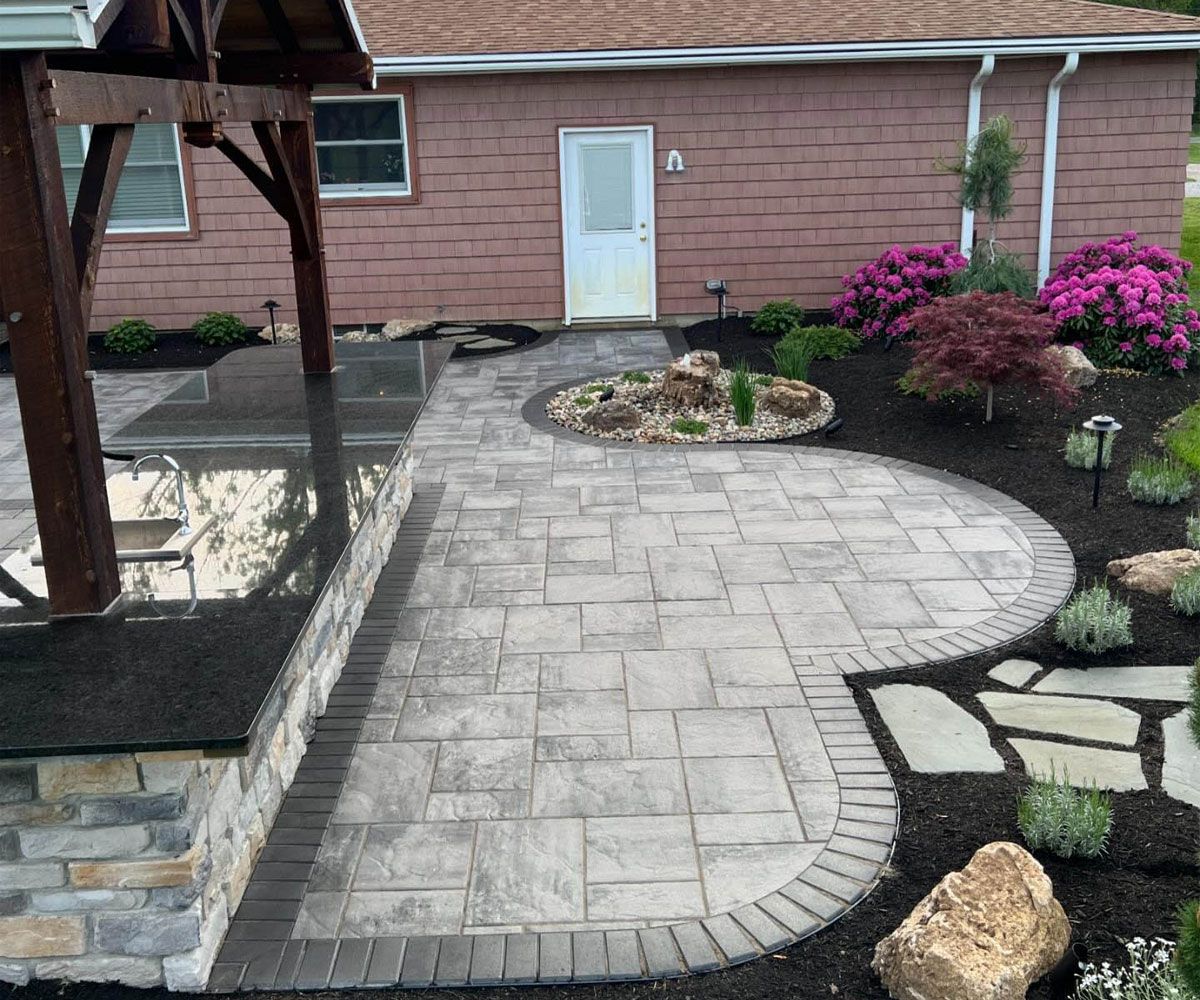 Fairlawn, OH outdoor living spaces with pavilion, outdoor kitchen, paving stone patio, and water feature natural stone bubbler.