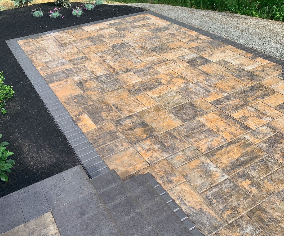 Hardscape paving stone patio installed with Unilock paver stones and black soldier course border in Fairlawn, Ohio backyard.