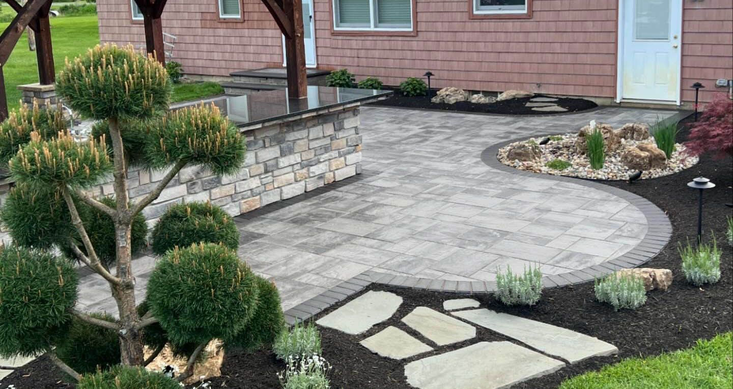 Bath, OH paving stone patio with outdoor kitchen covered by pavilion, water features and landscape lighting designed and installed by Chidsey Landscape & Design