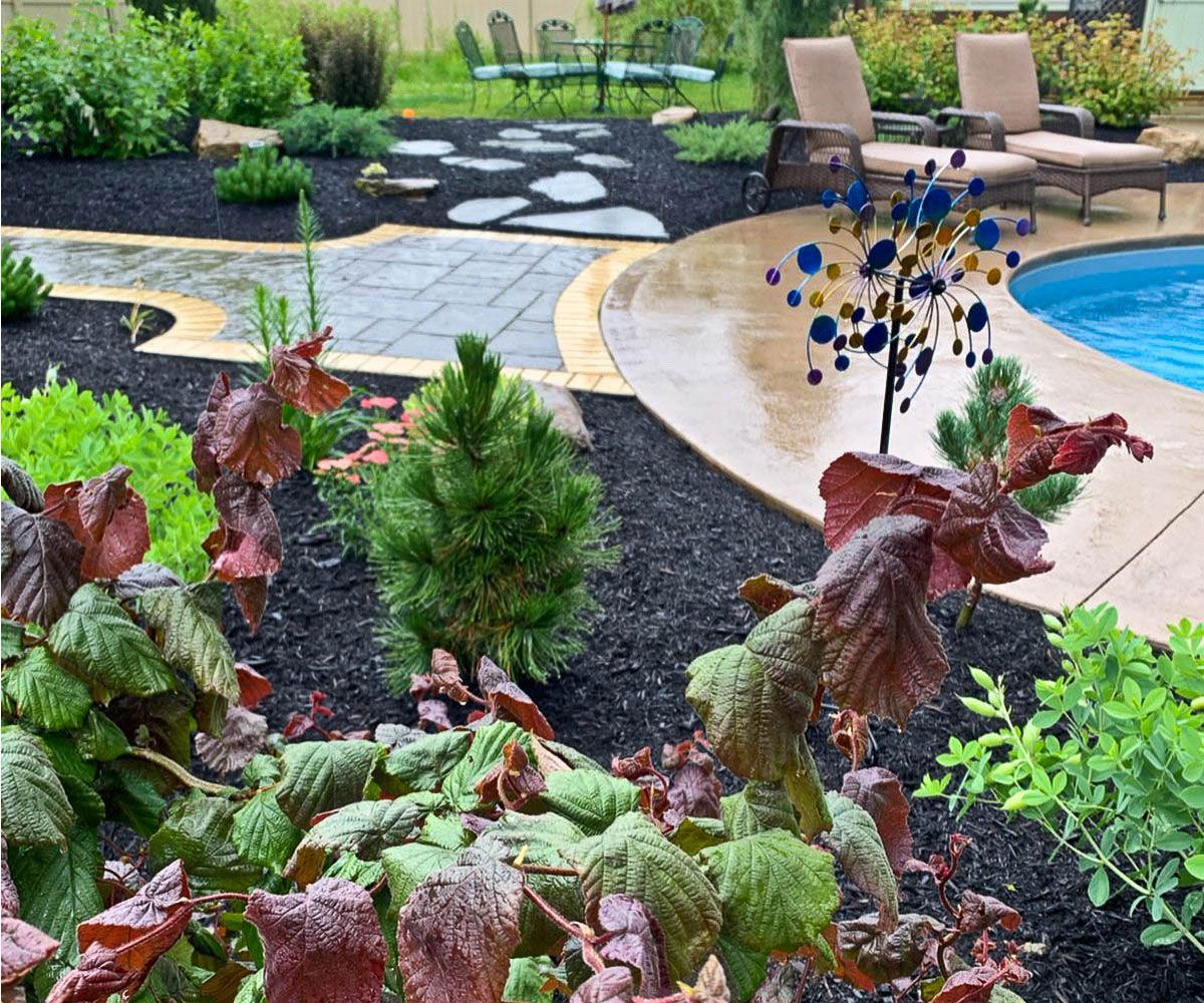 Layered garden bed installation with perennials and shrubs that softens walkway hardscape in Cuyahoga County, Ohio