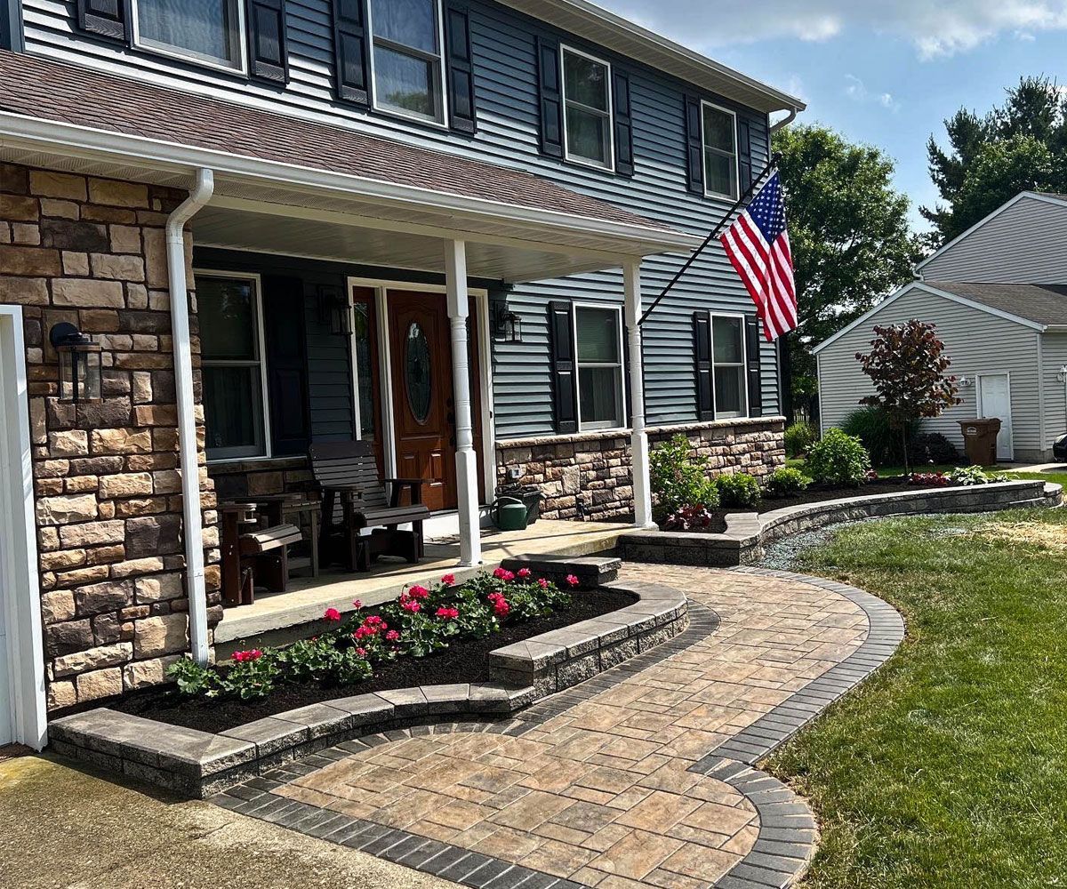 Curved paver front walkway of Northeast Ohio with wall block retaining wall and planting beds with flowers