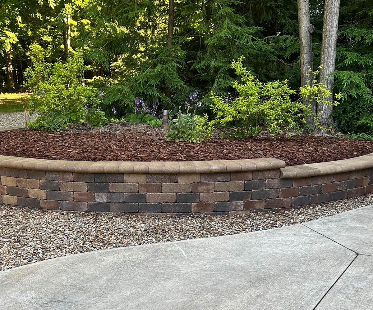 Retaining wall with garden plantings at front of Fairlawn, Ohio home near driveway.