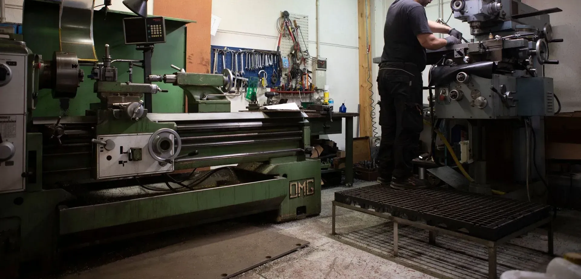 Macchinista che aziona una grande macchina industriale in un'officina con attrezzature verdi e nere