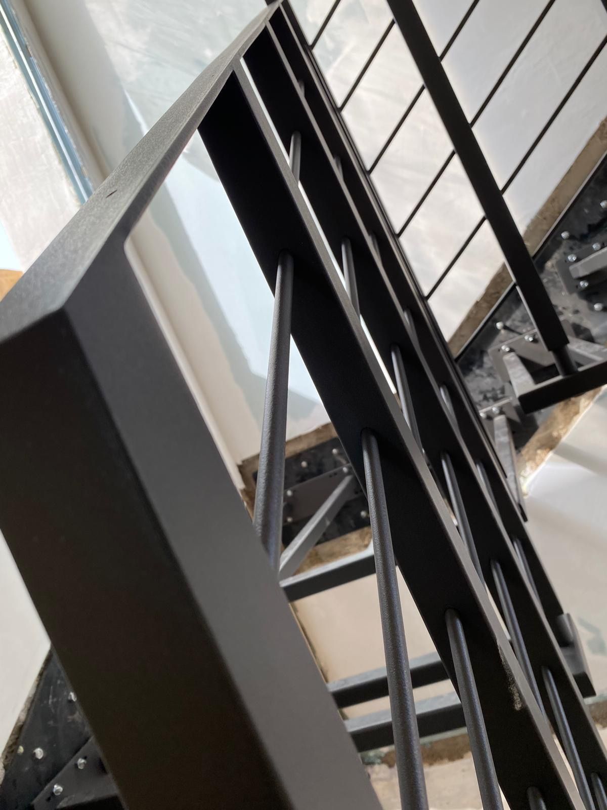 Ringhiera di una scala in metallo nero vista di profilo all'interno di un edificio.