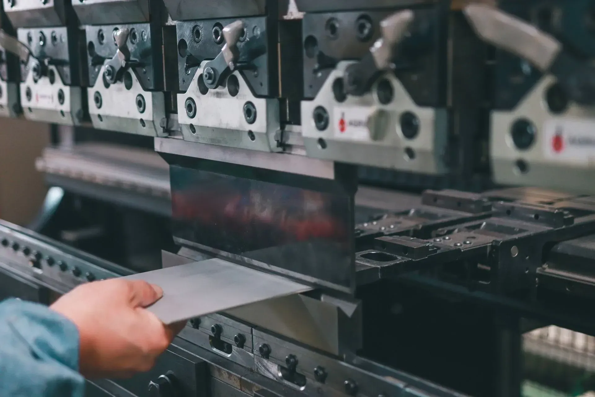 In una fabbrica, una lamiera viene inserita manualmente in un macchinario industriale.