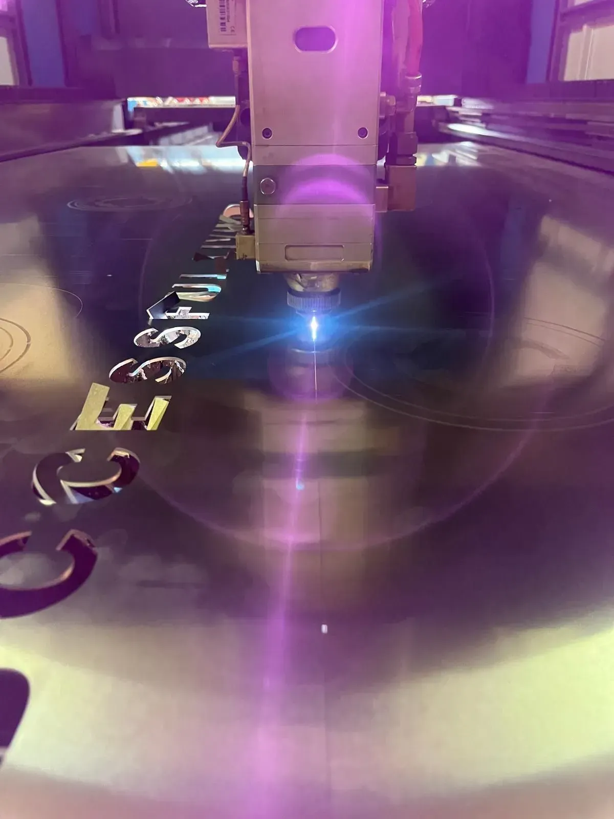 Incisione laser di un testo su una superficie nera lucida con riflessi viola.